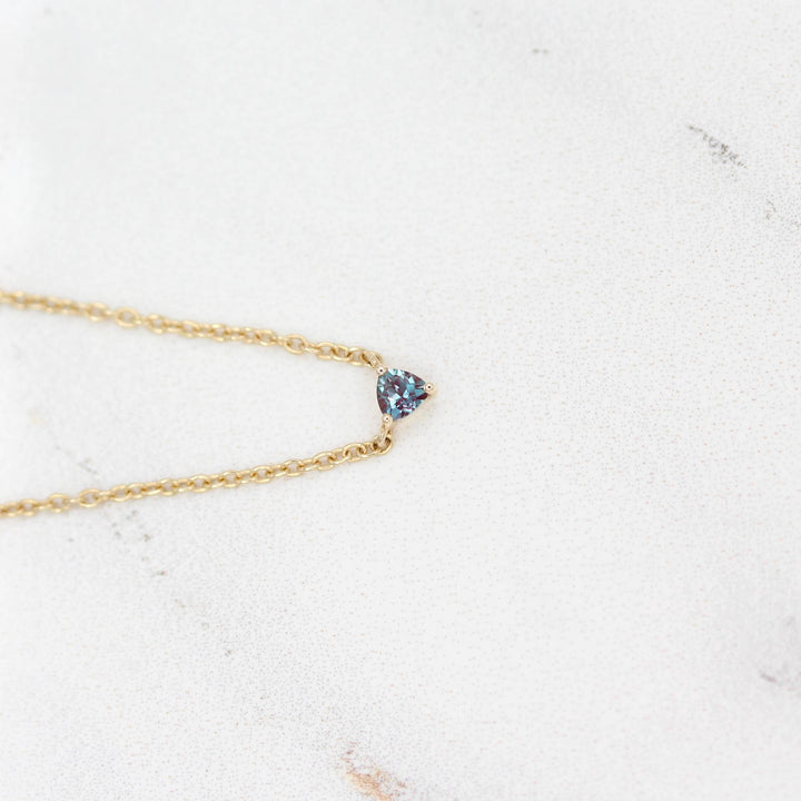 The June Birthstone Tiny Trillion Necklace with Alexandrite in Yellow Gold against a white background