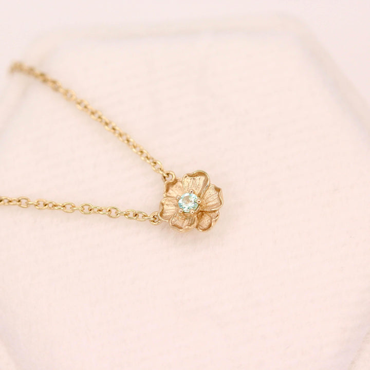 The March Birthstone Poppy Necklace with Aqua Spinel in Yellow Gold against a white velvet ring box