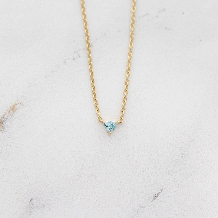 The March Tiny Trillion Birthstone Necklace with Aqua Spinel in Yellow Gold against a white background