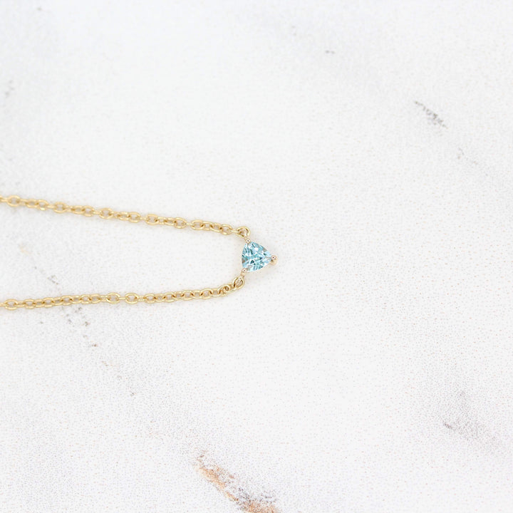 The March Tiny Trillion Birthstone Necklace with Aqua Spinel in Yellow Gold against a white background