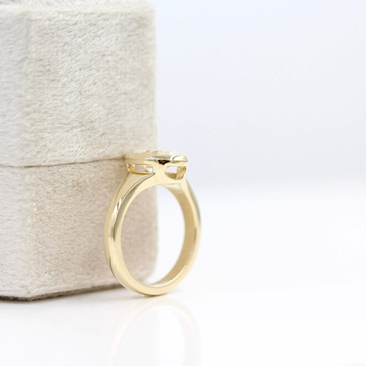 The Billie Ring (Oval) in Yellow Gold with 2ct Lab-Grown Diamond leaning against a white velvet ring box