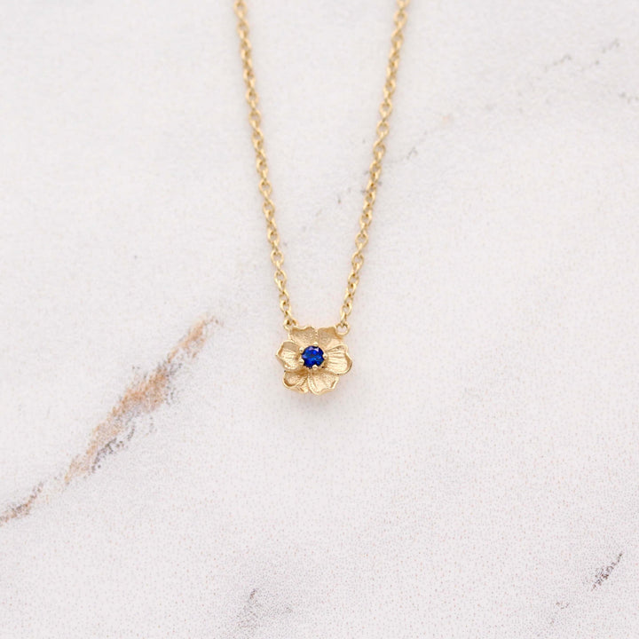 The September Birthstone Poppy Necklace with Blue Sapphire in Yellow Gold against a white background