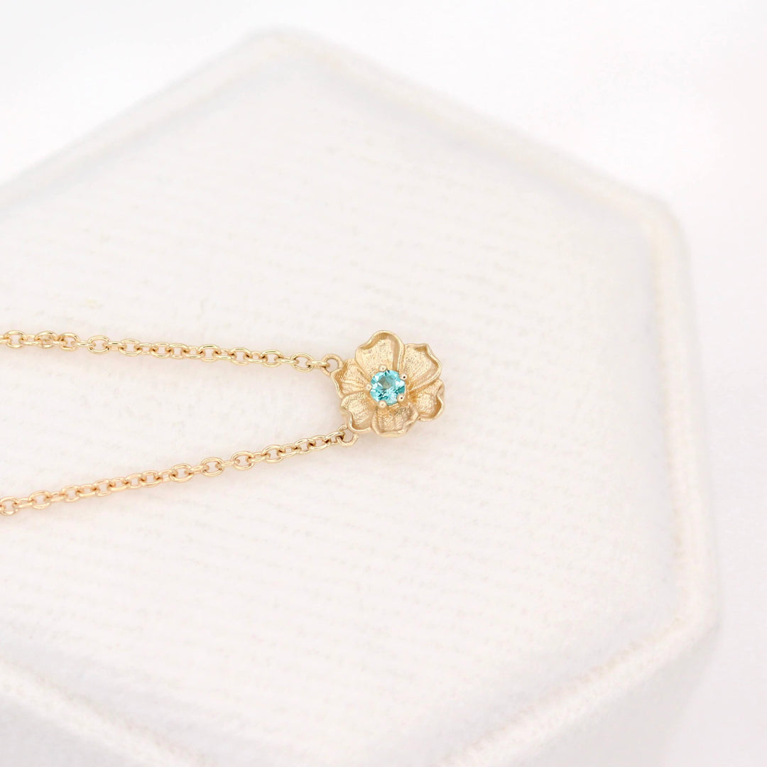 The August Birthstone Poppy Necklace with Chrysoberyl in Yellow Gold against a white velvet ring box