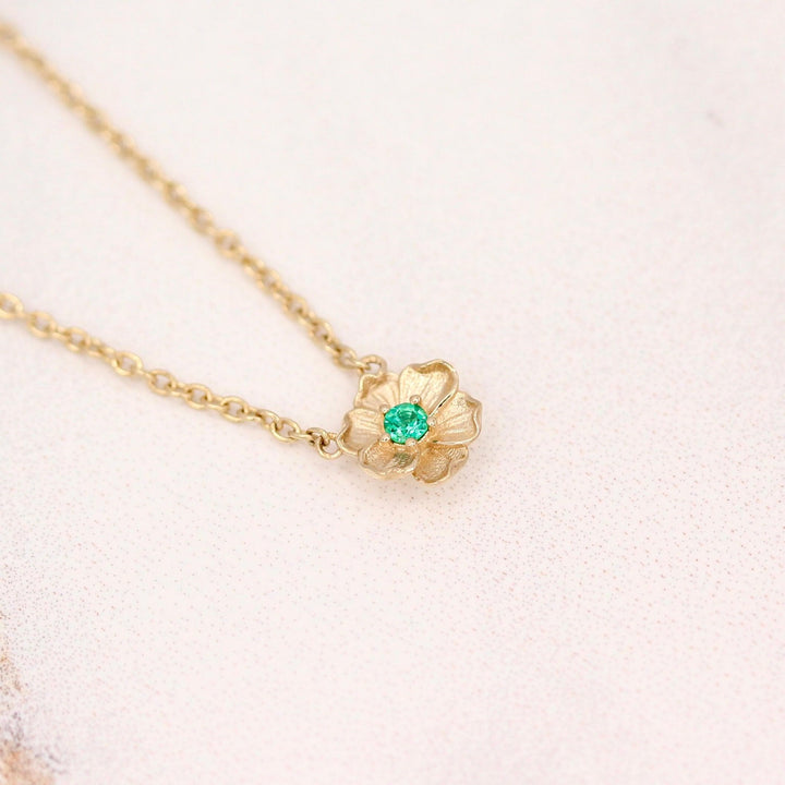 The May Birthstone Poppy Necklace with Emerald in Yellow Gold against a white background