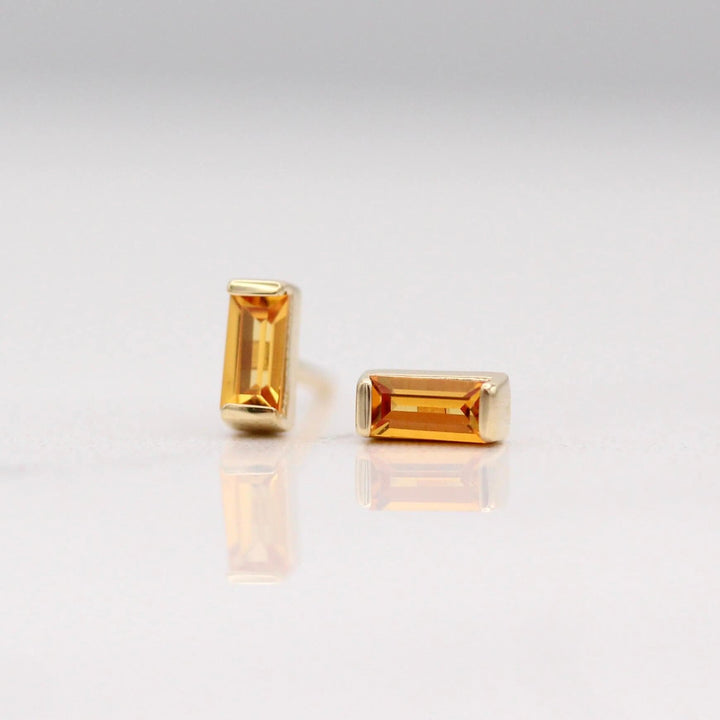 The November Baguette Birthstone Earrings with Gold Sapphire in Yellow Gold against a white background