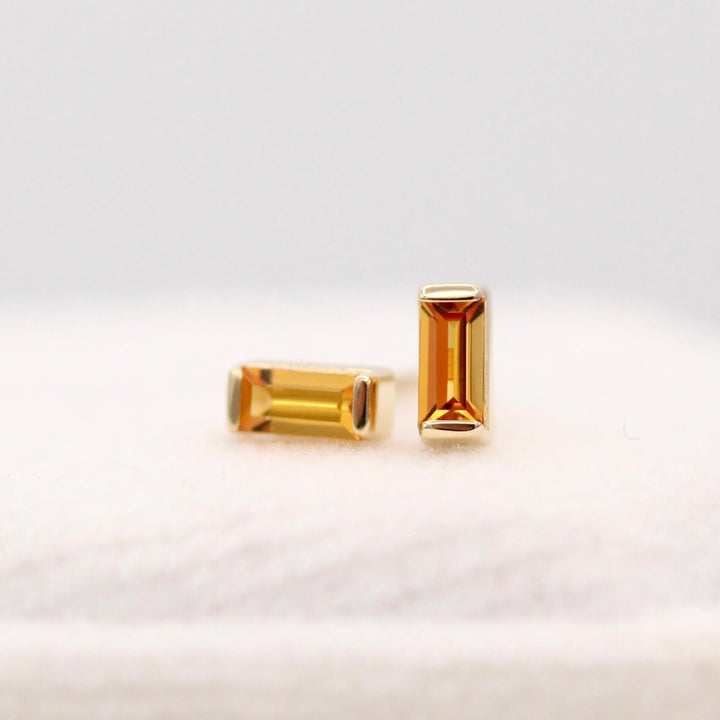 The November Baguette Birthstone Earrings with Gold Sapphire in Yellow Gold atop of a white velvet ring box