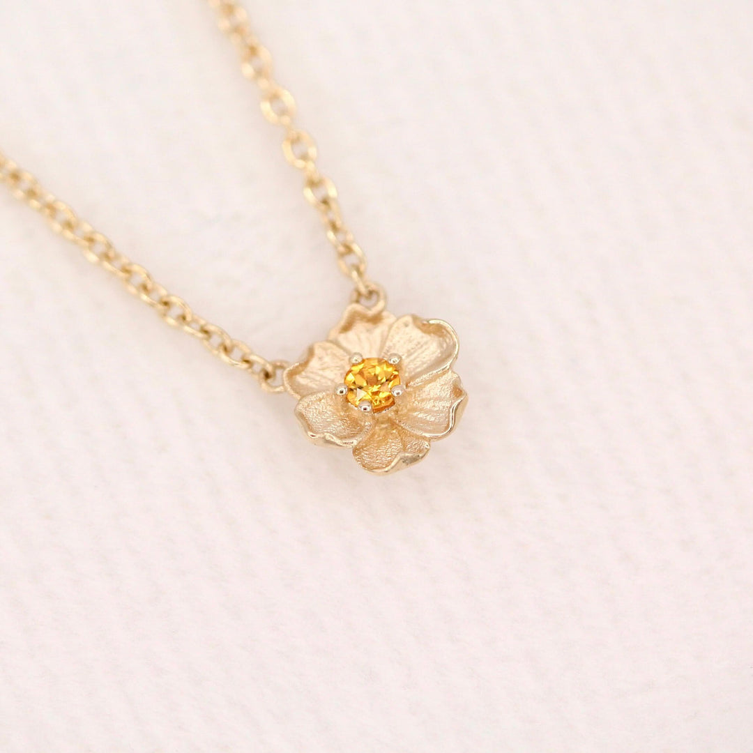 The November Birthstone Poppy Necklace with Gold Sapphire in Yellow Gold against a white velvet ring box