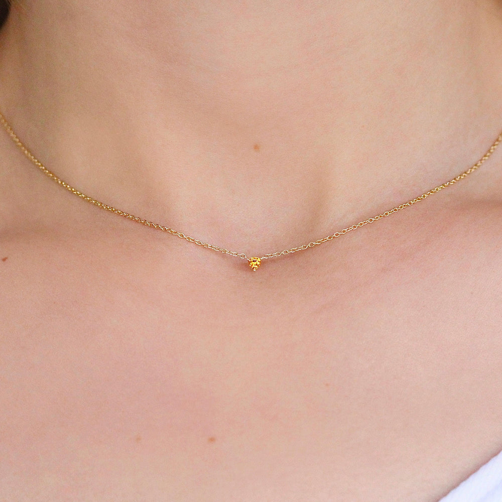 The November Birthstone Tiny Trillion Necklace with Gold Sapphire in Yellow Gold against a white background modeled