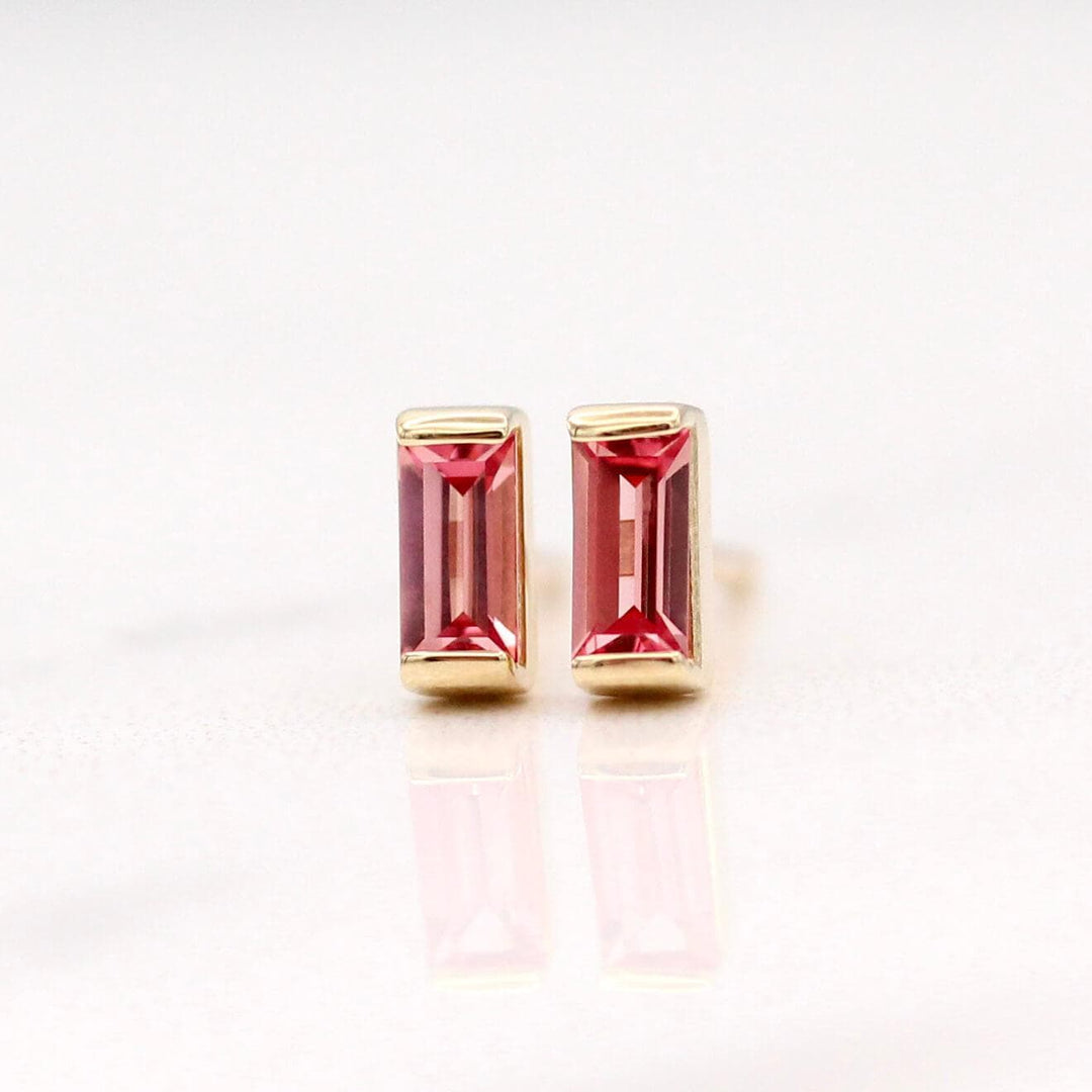 The January Birthstone Baguette Earrings with Padparadscha Sapphire in Yellow Gold against a white background