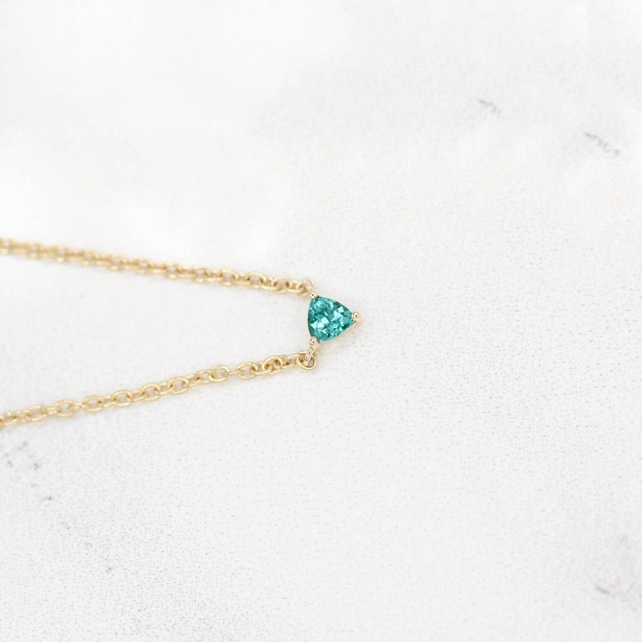 The December Birthstone Tiny Trillion Necklace with Paraiba Spinel in Yellow Gold against a white background