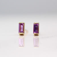 The February Baguette Birthstone Earrings with Purple Sapphire in Yellow Gold against a white background