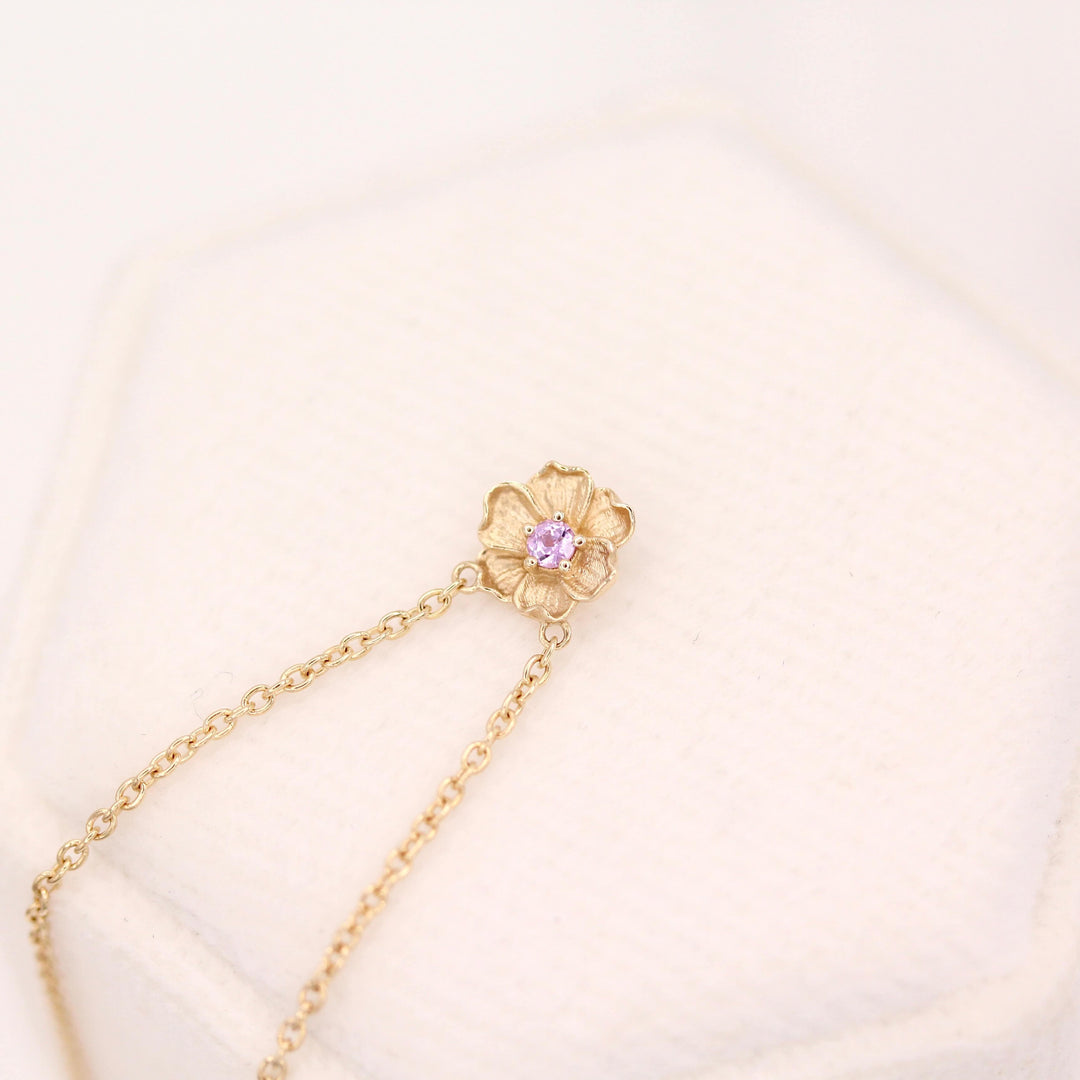 The February Birthstone Poppy Necklace with Purple Sapphire in Yellow Gold against a white velvet ring box