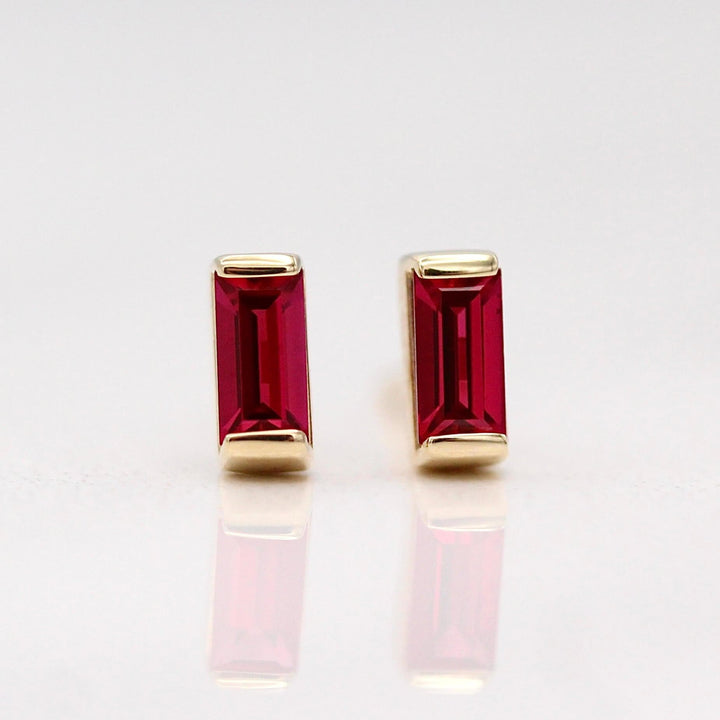 The July Baguette Birthstone Earrings with Ruby in Yellow Gold against a white background