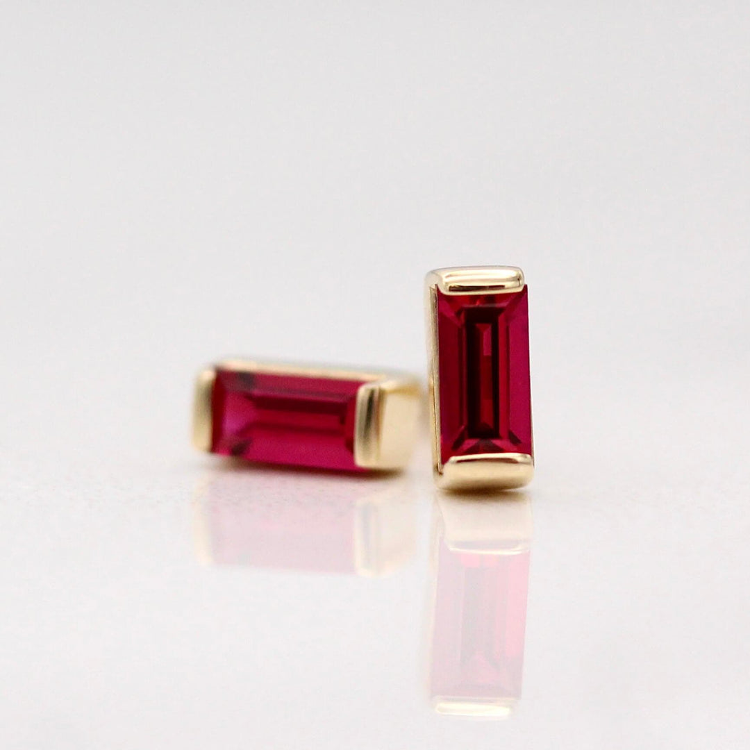 The July Baguette Birthstone Earrings with Ruby in Yellow Gold against a white background