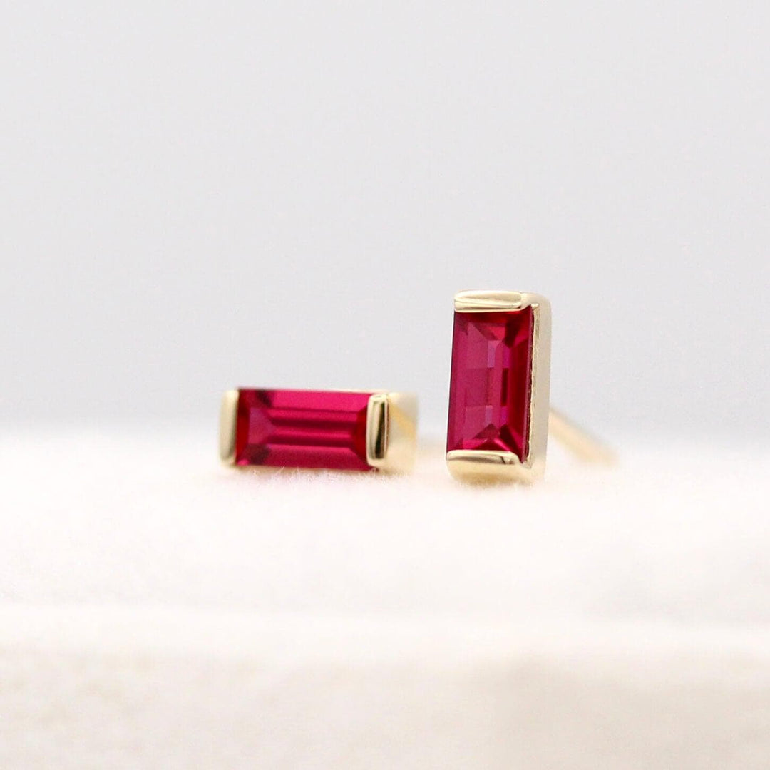 The July Baguette Birthstone Earrings with Ruby in Yellow Gold atop of a white velvet ring box