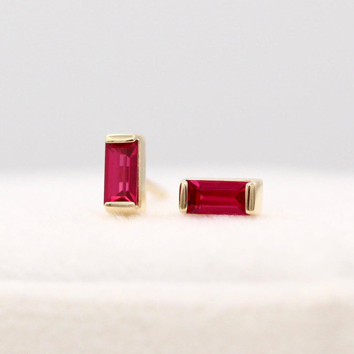 The July Baguette Birthstone Earrings with Ruby in Yellow Gold atop of a white velvet ring box