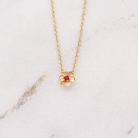 The July Birthstone Poppy Necklace with Ruby in Yellow Gold against a white background