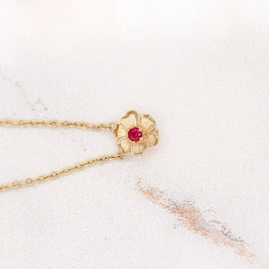 The July Birthstone Poppy Necklace with Ruby in Yellow Gold against a white background