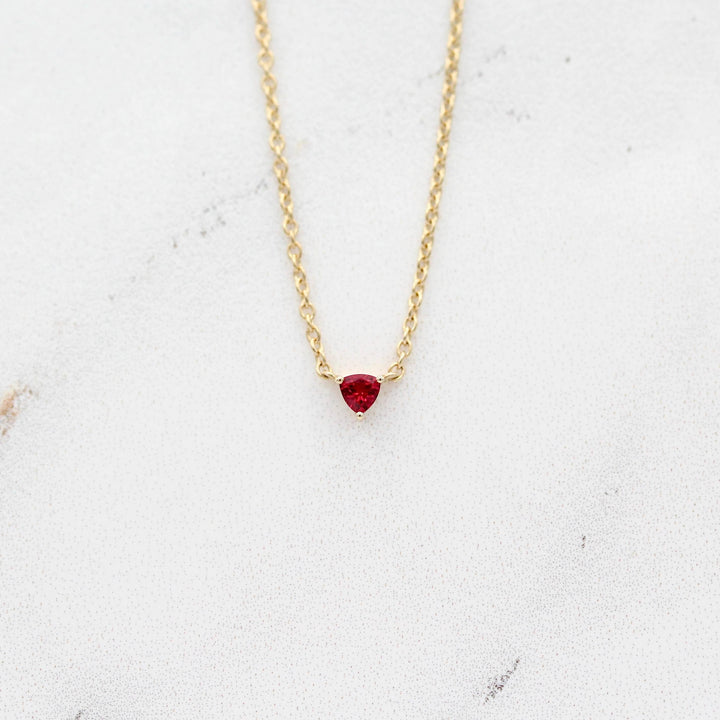 The July Birthstone Tiny Trillion Necklace with Ruby in Yellow Gold against a white background