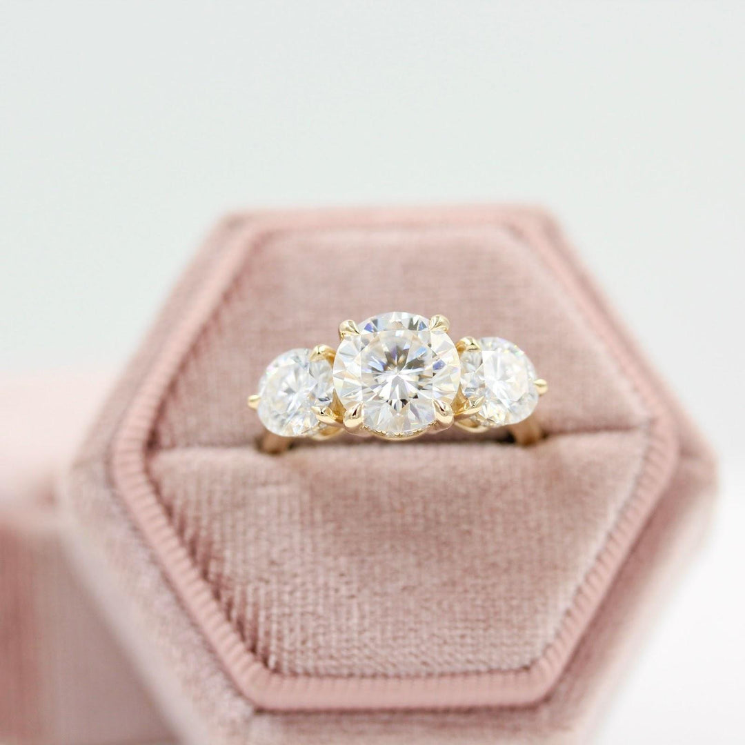 three-stone old money engagement ring in a pink velvet box